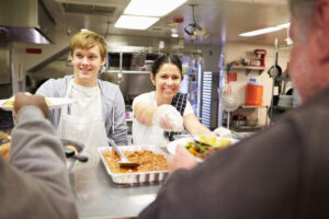 Volunteers serving food from a community hockey club canteen servery.